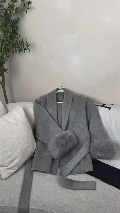 “Female model wearing Hepburn woolen coat with lace-up sleeves and faux-fur cuffs, styled in city winter outfit”